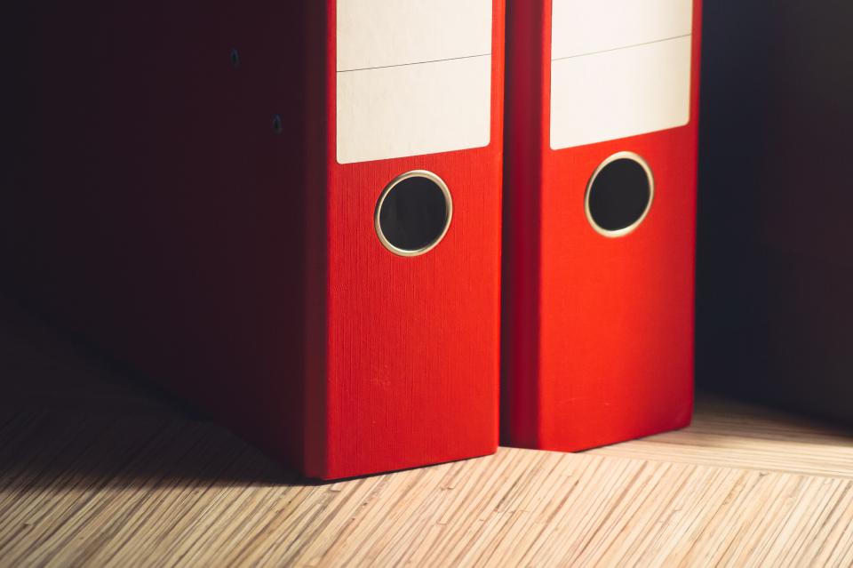 Piles de dossiers administratifs empilées sur un bureau, symbole des tâches qu'une automatisation IA PME peut reprendre